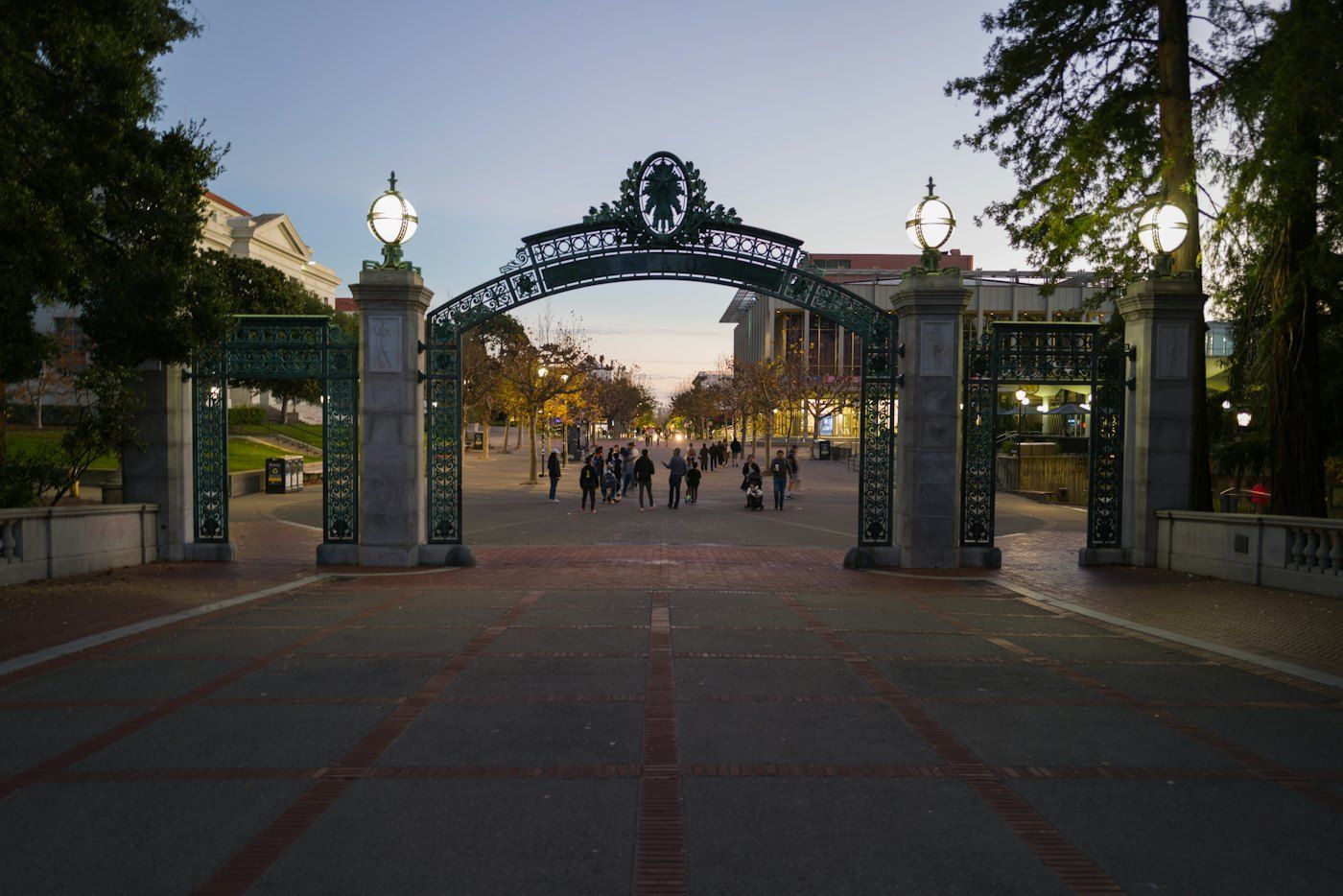 Sather Gate in Berkeley at dusk with people walking through