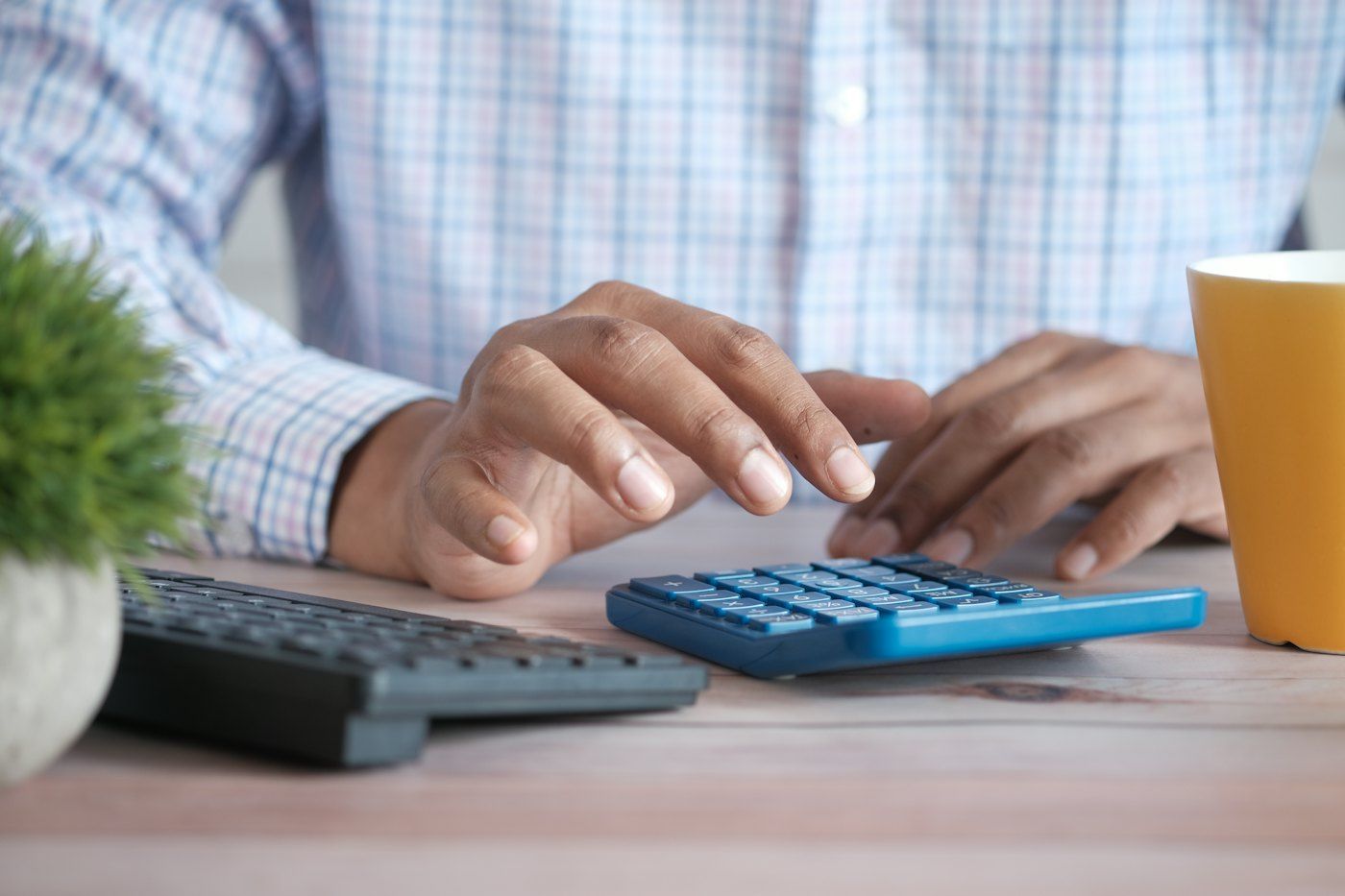 A person working through figures with a calculator and notebook at a desk