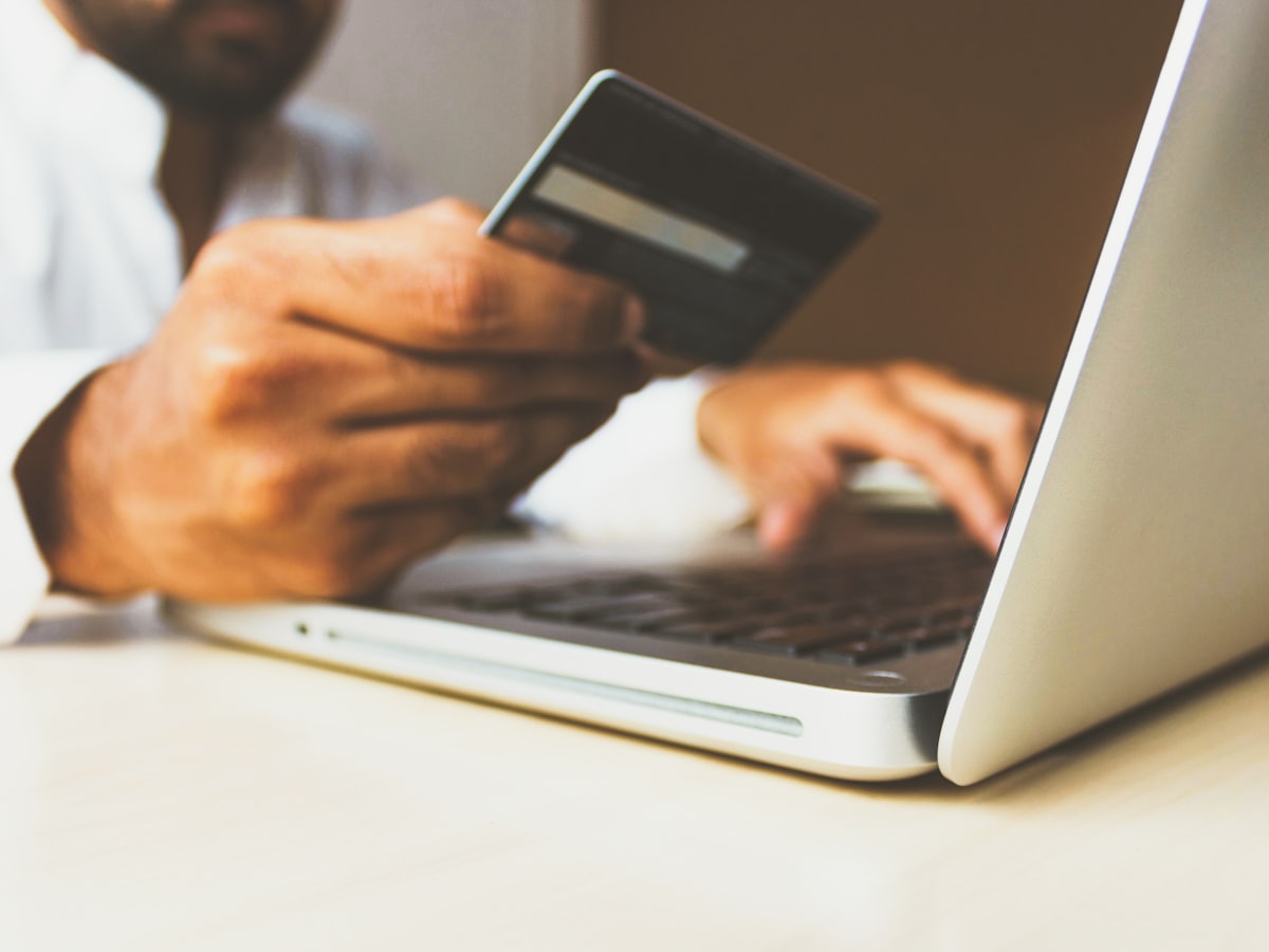 A person shopping online with a credit card and laptop